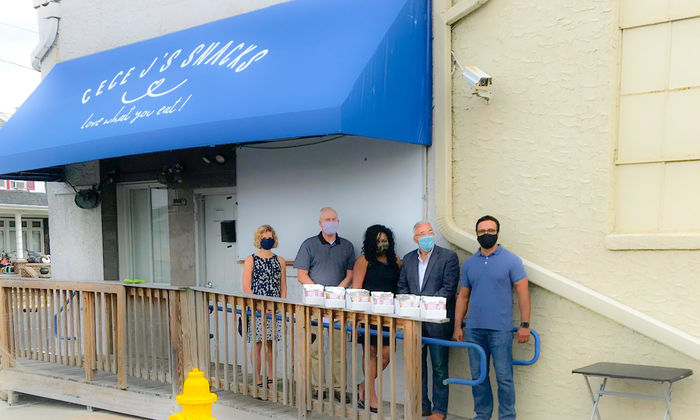 five people posed in front of a blue awning