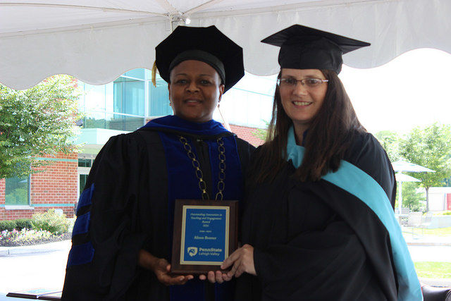 two women pose with a plaque