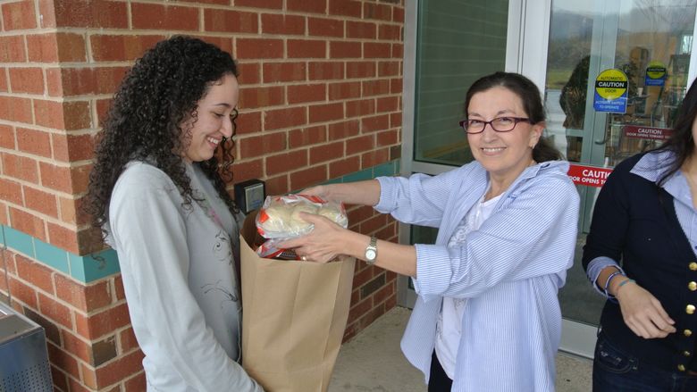 Faculty member and student packing a bag of food donations