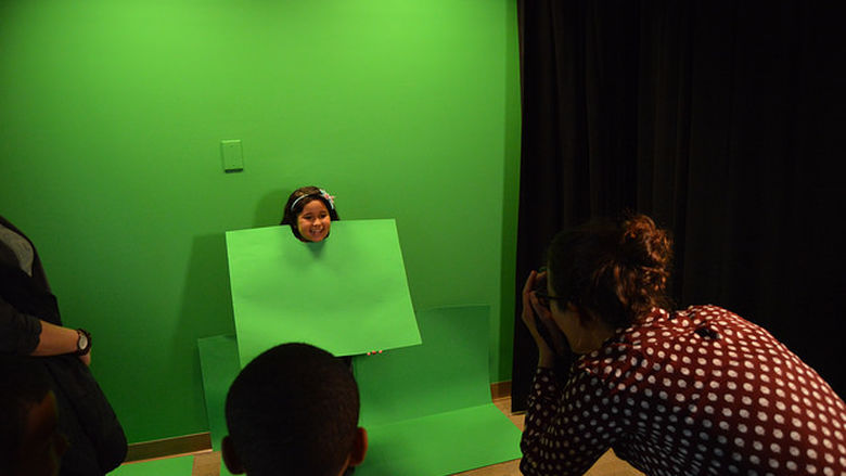 A little girl poses in front of green screen