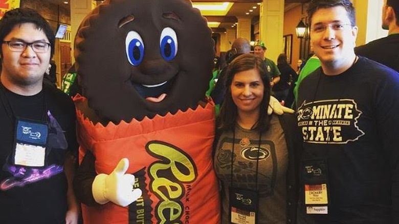 three students posing with Reeses mascot 