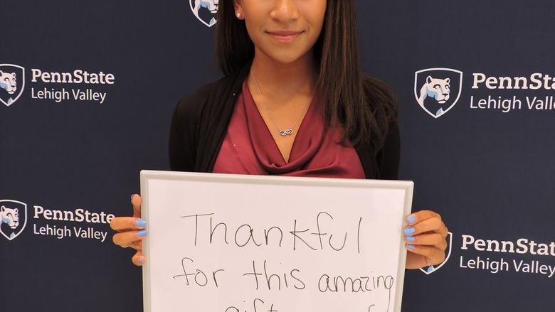 student with a sign saying Thankful for this amazing gift