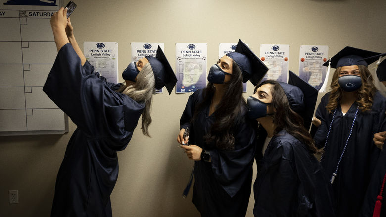 female women in cap and gown lining up for selfie photo