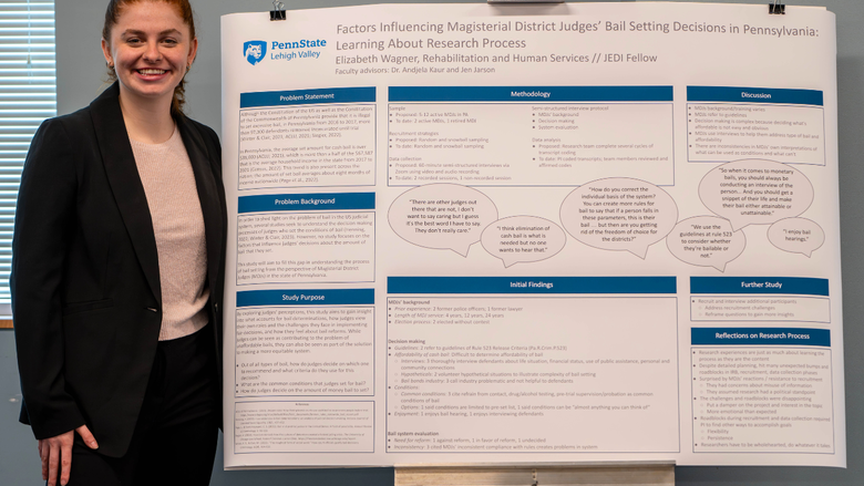 A student smiling next to a research poster