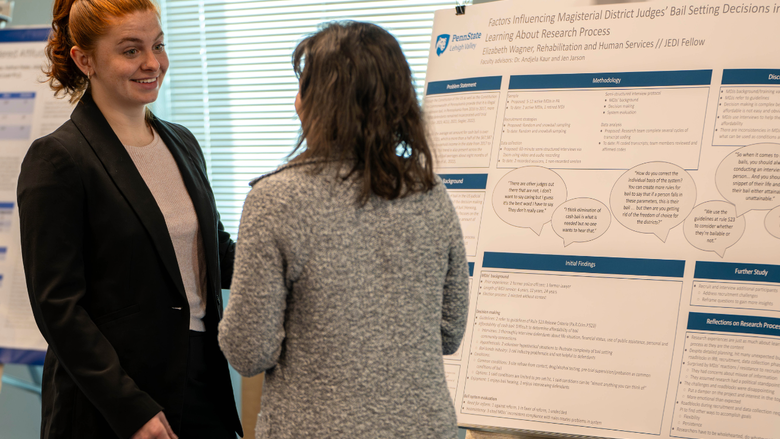 Two people talk in front of a research poster