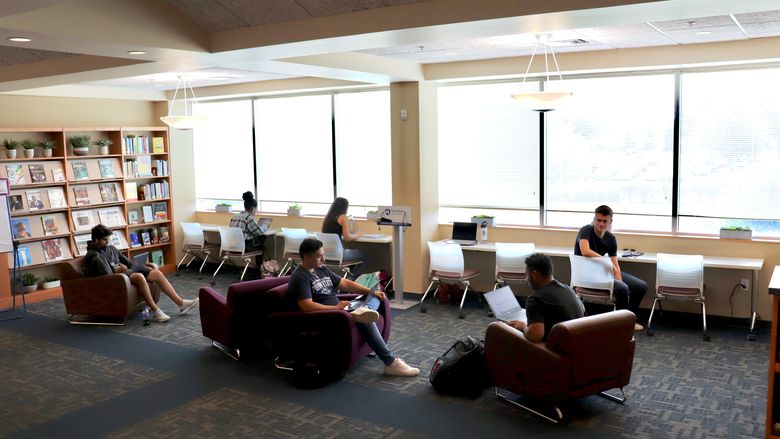 students studying in lounge chairs and desk chairs in library