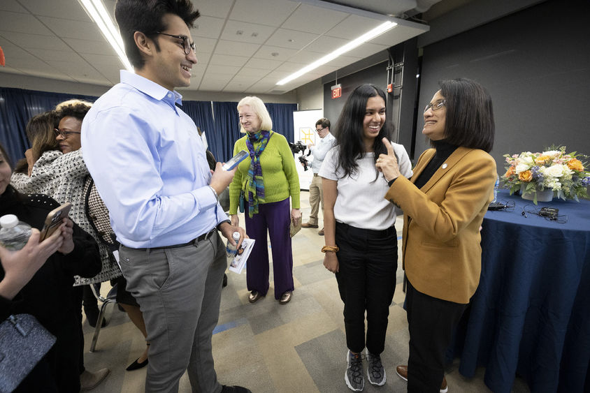 President Bendapudi chats with several students in a room.