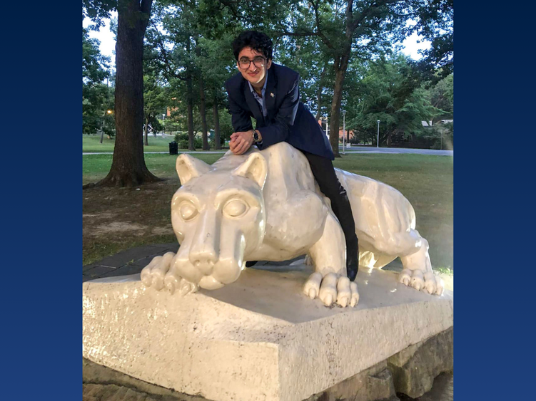 a male student smiling next to the lion shrine 