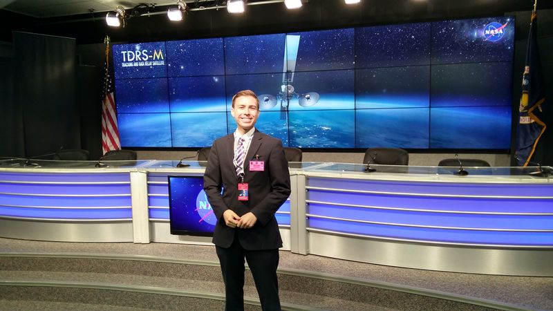 Drew Anderson in front of desk at NASA briefing room