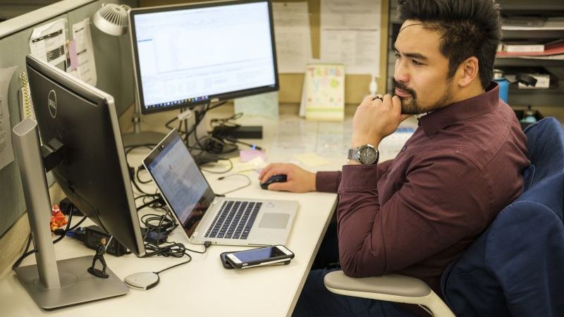 man sitting at desk staring at computer screen