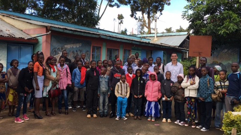 Nick Miller poses with children in Kenya