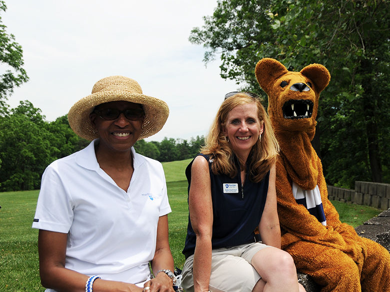 two staff members posing together with the nittany lion mascot