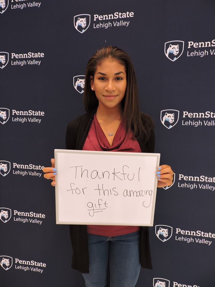 student with a sign saying Thankful for this amazing gift