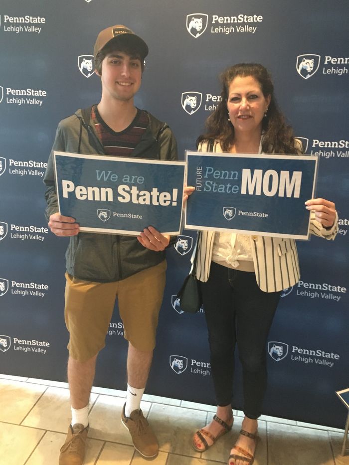 a young man and a woman who is his mom holding PSU signs