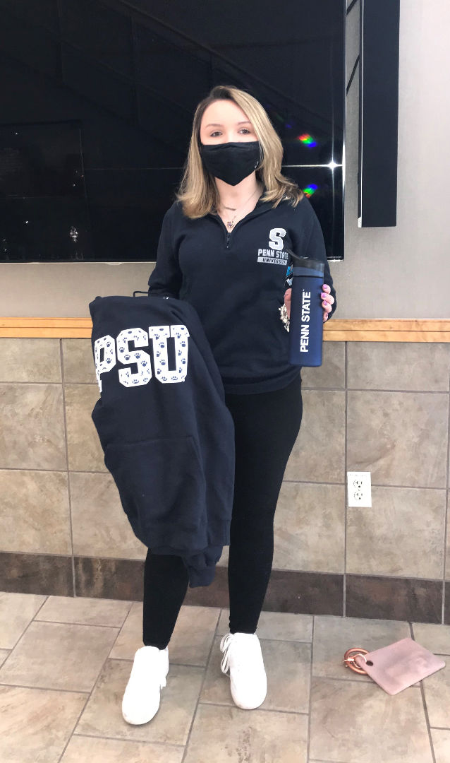 Female student holding a Penn State branded water bottle and sweatshirt.