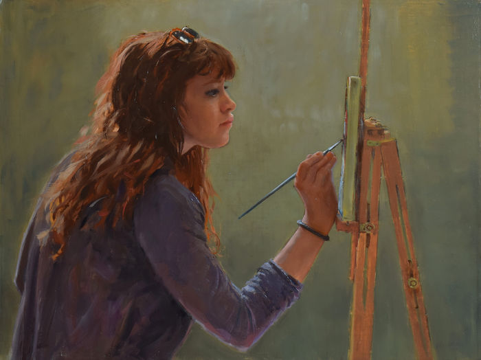 profile of woman painting on an easel with a paintbrush