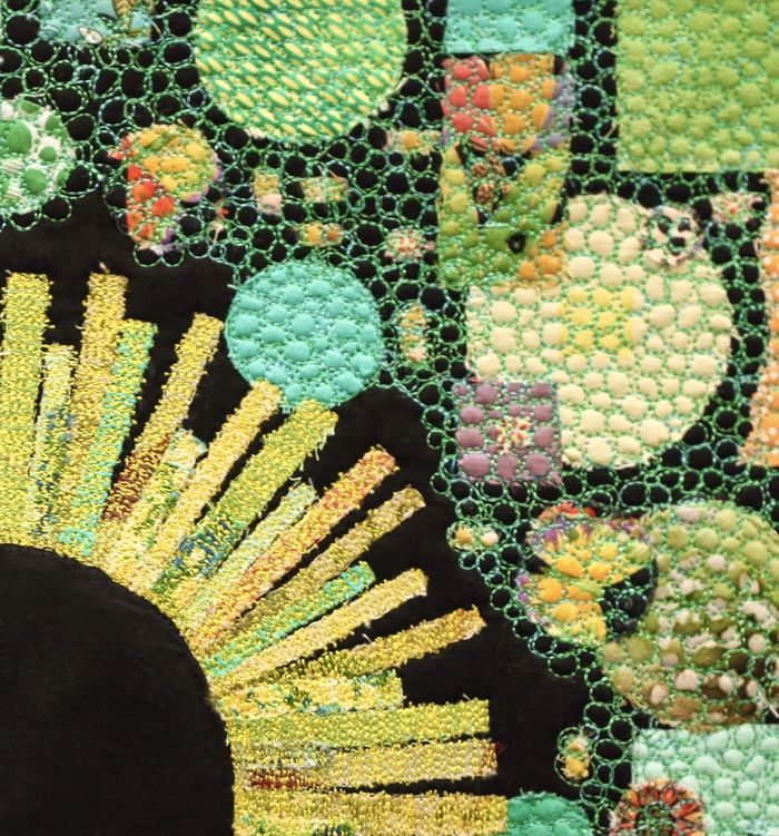 textile artwork showing a flower and green and blue shapes
