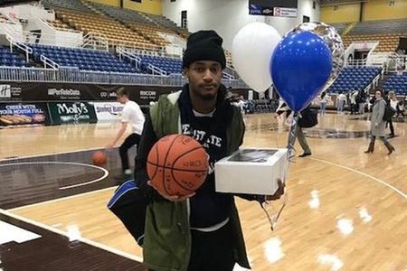 Basketball player with cake and balloons on court