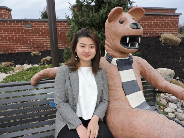 student sitting next to nittany lion statue
