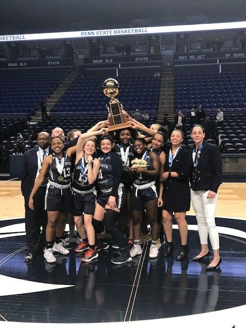 basketball team and coaches holding up trophy