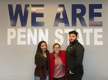three students under We Are Penn State sign