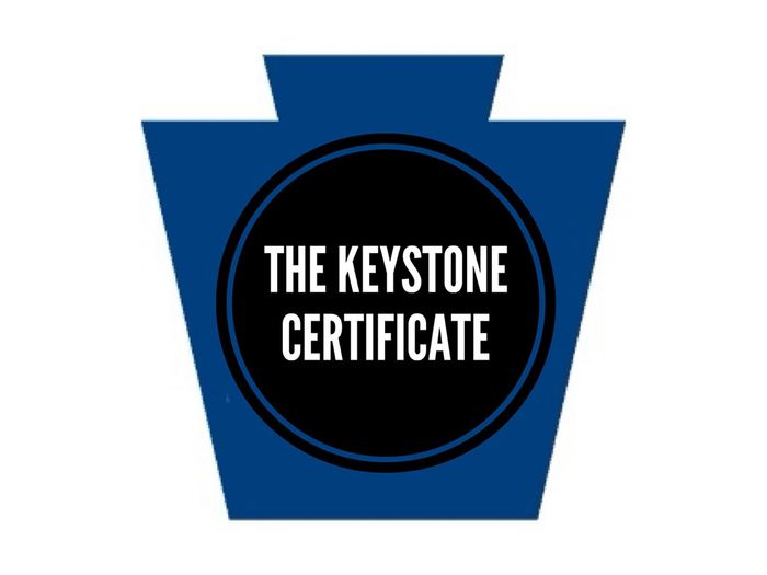 A dark blueKeystone shape with a black circle in the middle and the words "Keystone Certificate" inside the circle.