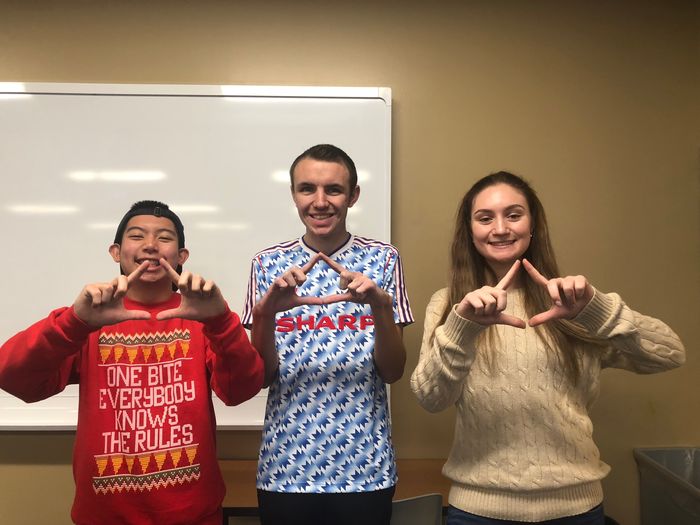 Three college students making THON diamond with hands