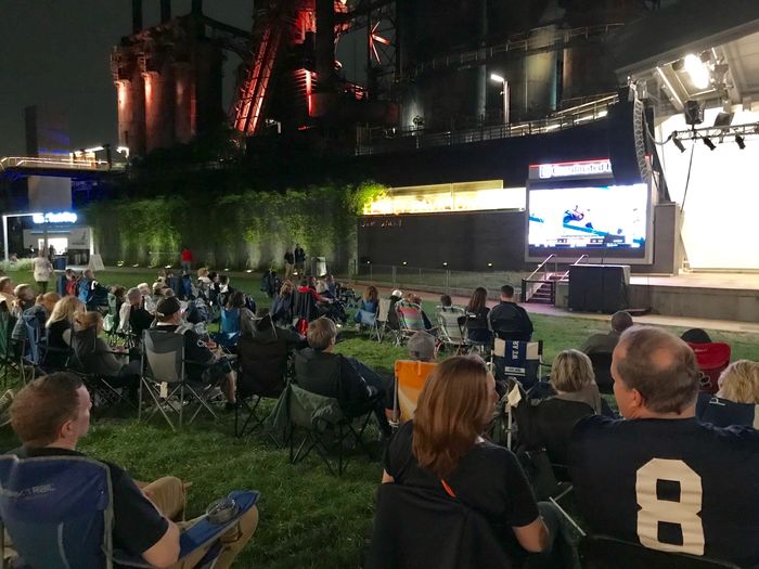 large group of people watching football game on big screen in front of Levitt Pavilion SteelStacks