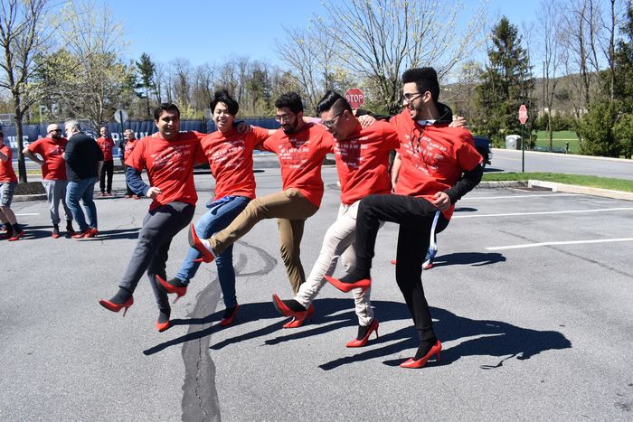 men kicking their legs wearing red heels and red shirts