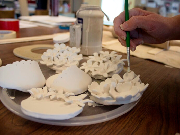 a hand paints a floral sculpture 