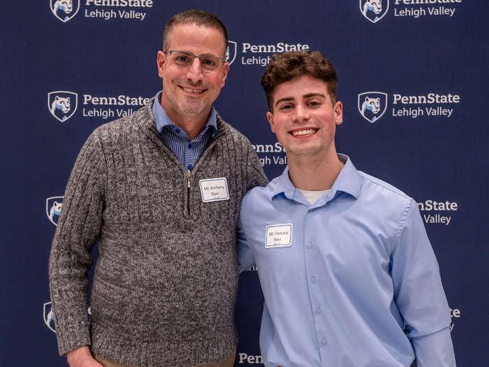 a male student smiles with his father in front of a Penn State Lehigh Valley sign
