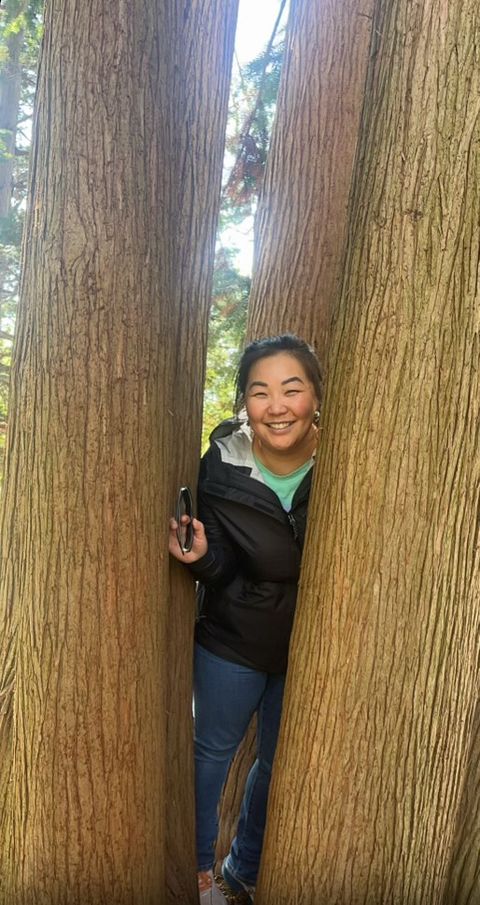 woamn smiling, standing between two trees.