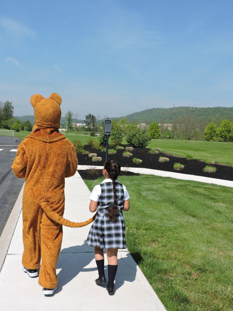 A little girl walks with Nittany Lion