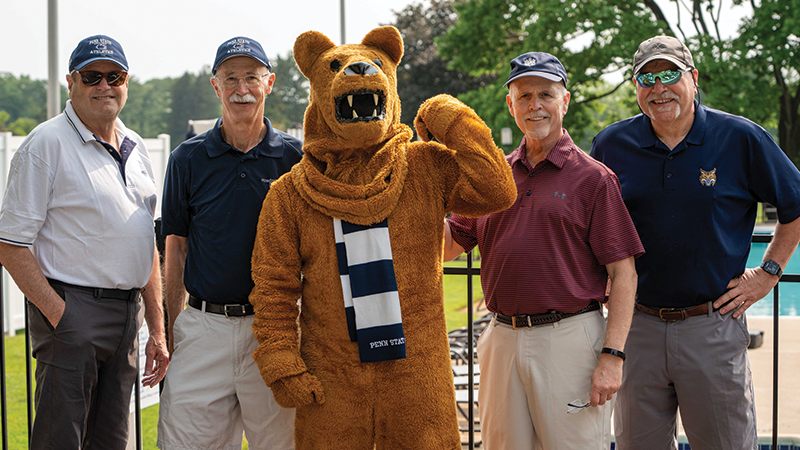 Four male golfers stand with the Nittany Lion mascot.