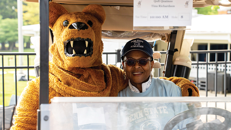 Dr. Richardson and Nittany Lion mascot sit in a golf cart.