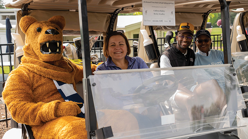 Nittany Lion mascot and woman sit in golf cart
