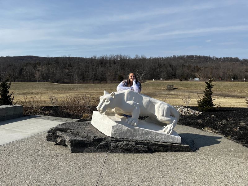 woman smiling leaning on Nittany Lion Statue 