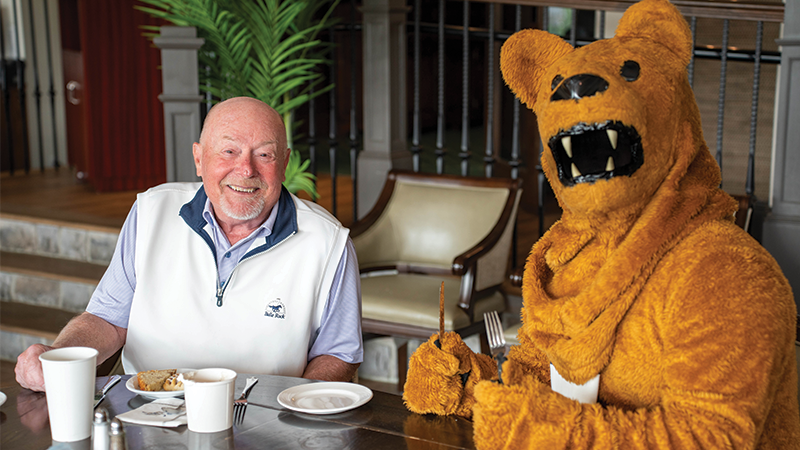 Man sitting at breakfast table wit the Nittany Lion mascot.