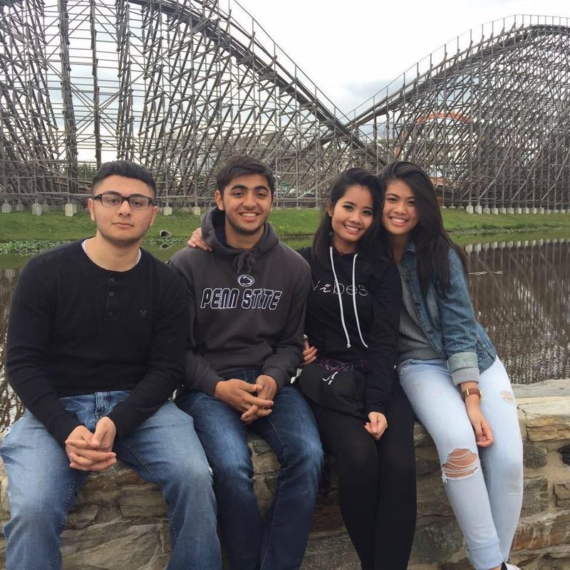 A group of students sit in front of a roller coaster