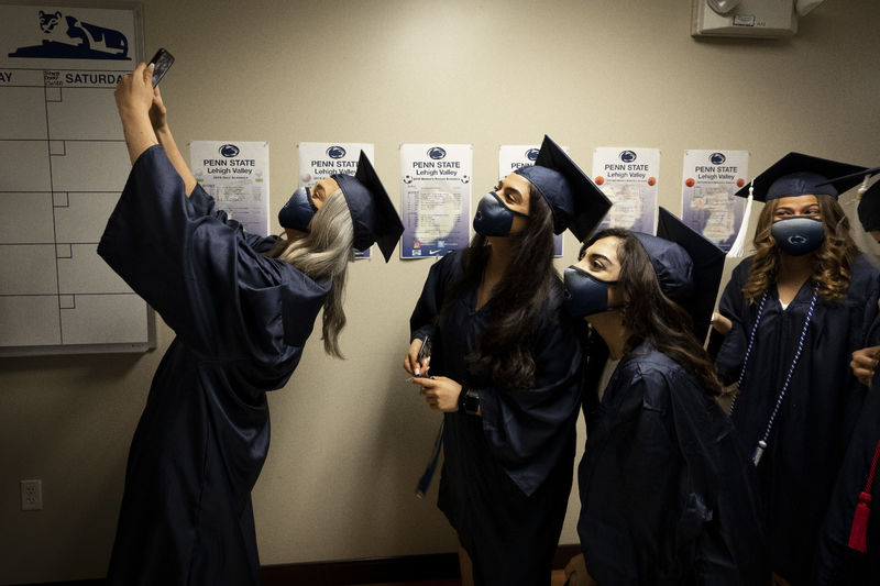 female women in cap and gown lining up for selfie photo