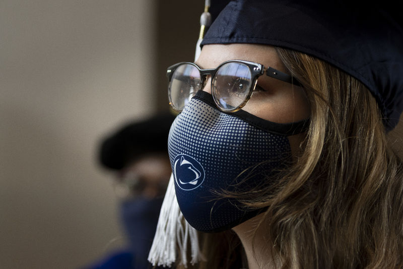 woman in glasses and mask with graduation cap on looking to the right
