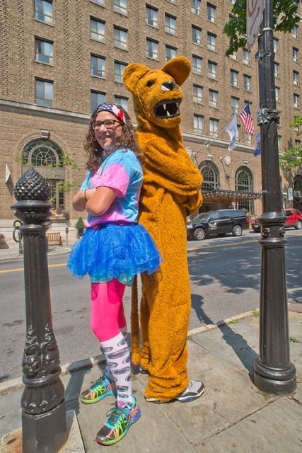 Young woman and Nittany Lion pose back to back in front of Hotel Bethlehem.