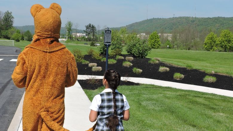 A little girl walks with Nittany Lion