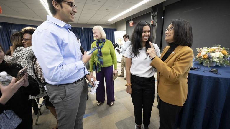 President Bendapudi chats with several students in a room.
