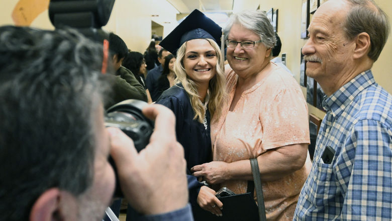 Graduate Hanna Morgan, in cap and gown, pauses for photo opportunities with her grandparents.