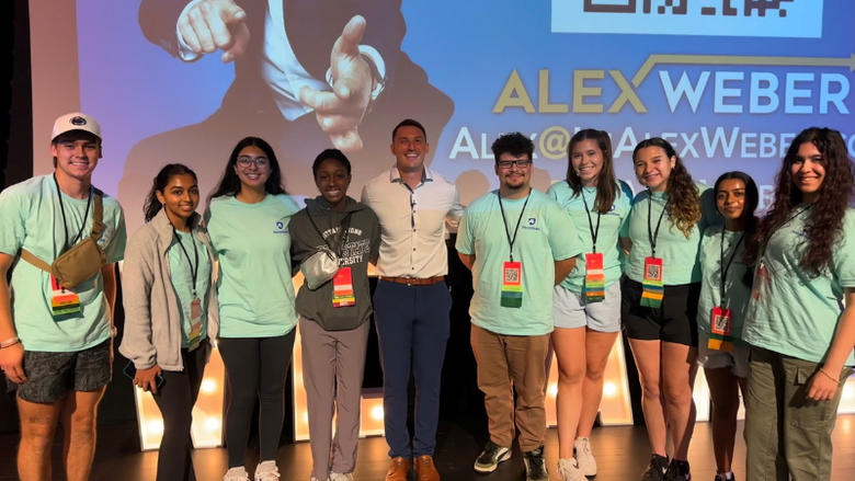 students smiling on a stage inside an auditorium 