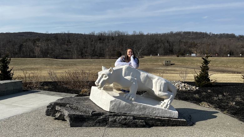 woman smiling leaning on Nittany Lion Statue 