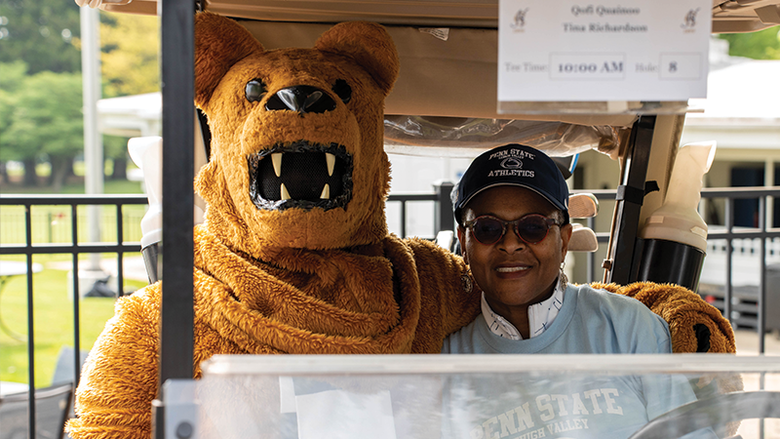 Dr. Richardson and Nittany Lion mascot sit in a golf cart.