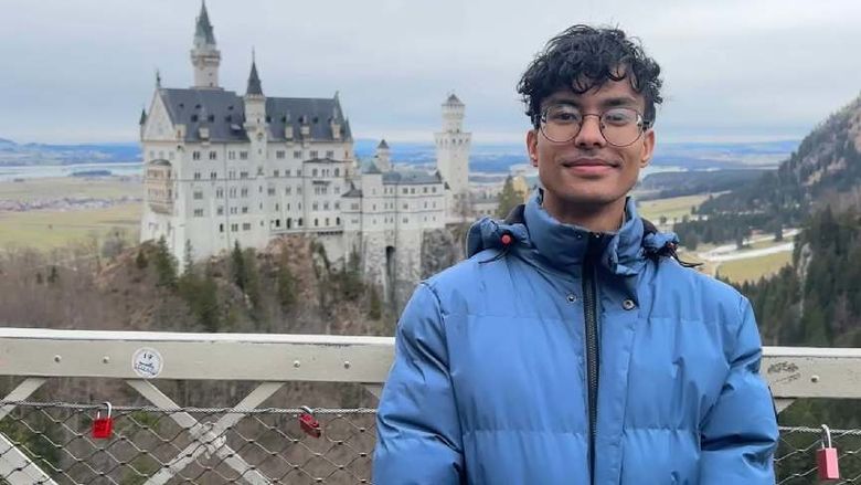 A student poses in front of a far-away castle