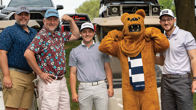 Four male golfers stand with the Nittany Lion mascot.